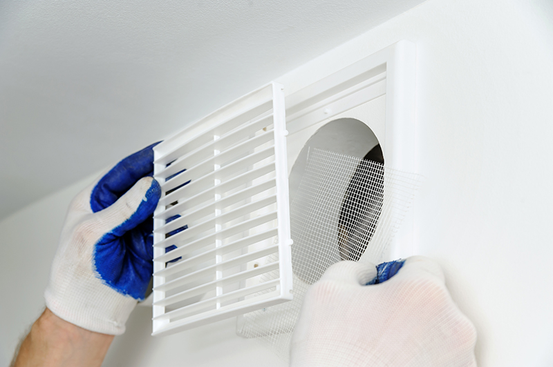 worker installs ventilation grille.