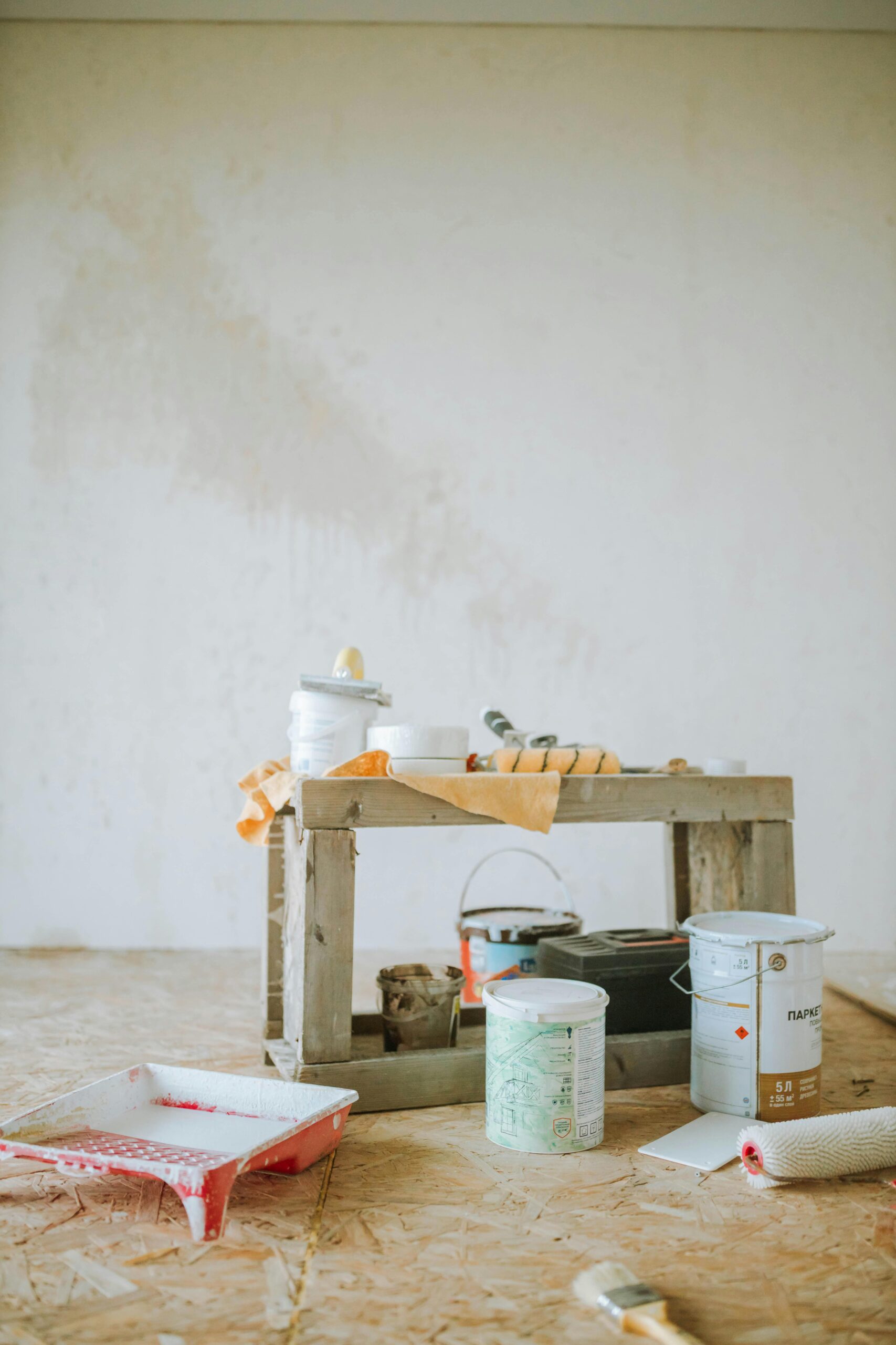 A collection of paint supplies for home renovation placed on the floor indoors, ready for wall painting.